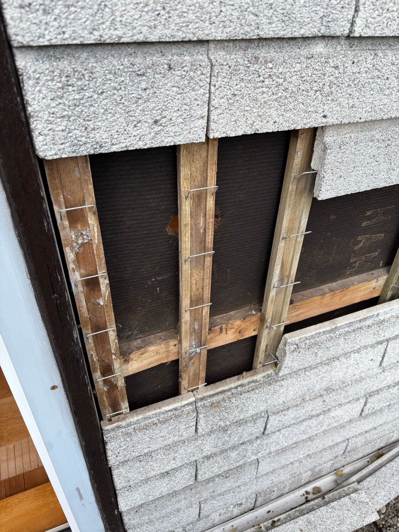 Exterior wall with exposed wood frame, insulation, and rough construction substructure visible