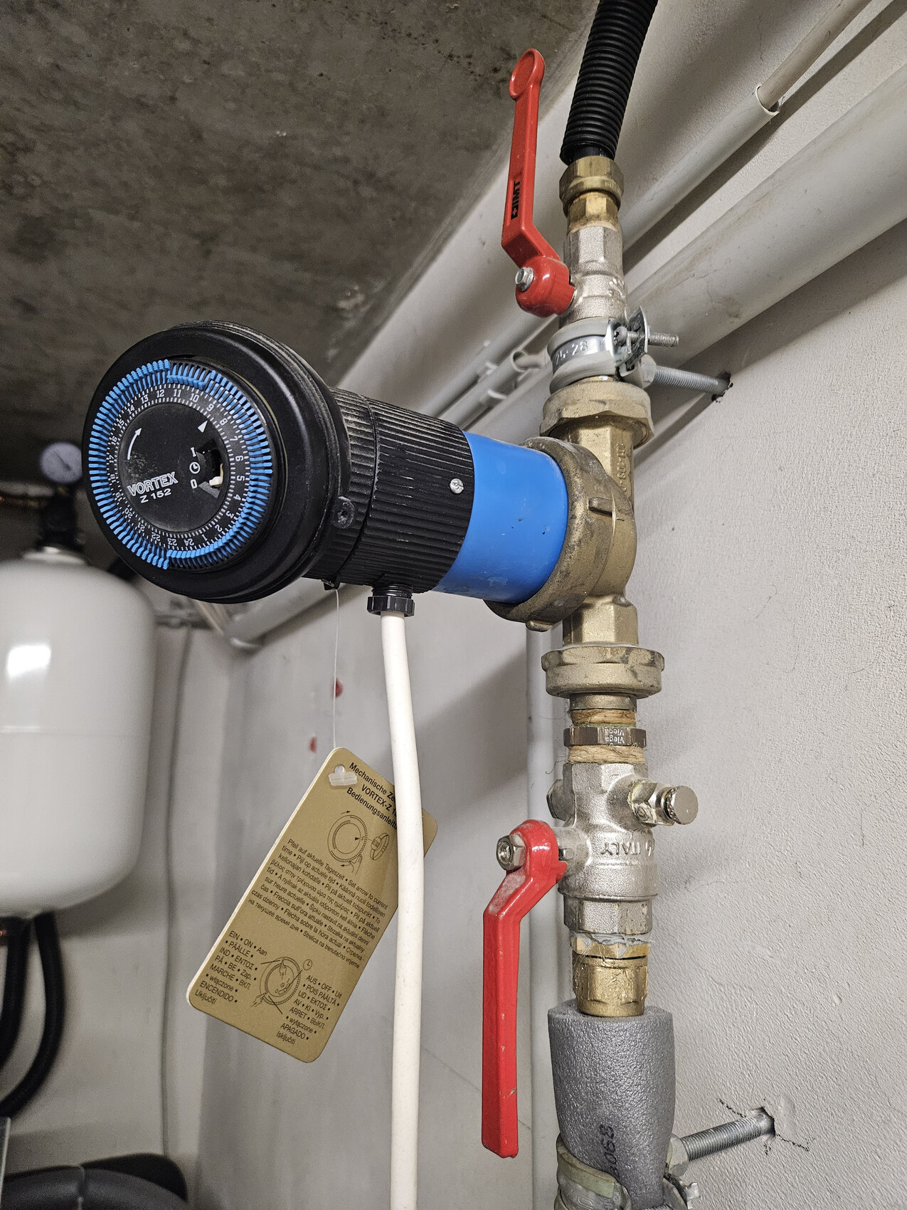 Water controller with blue housing, pressure gauge and red shut-off valve on the piping system.