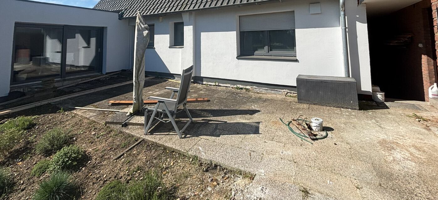 Garden terrace in front of the house during construction: chairs, sunshade frame, and materials.