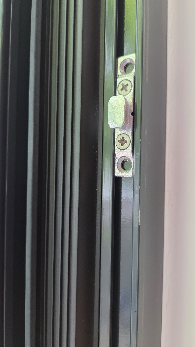 Close-up of a door frame with metal strike plate and screws.