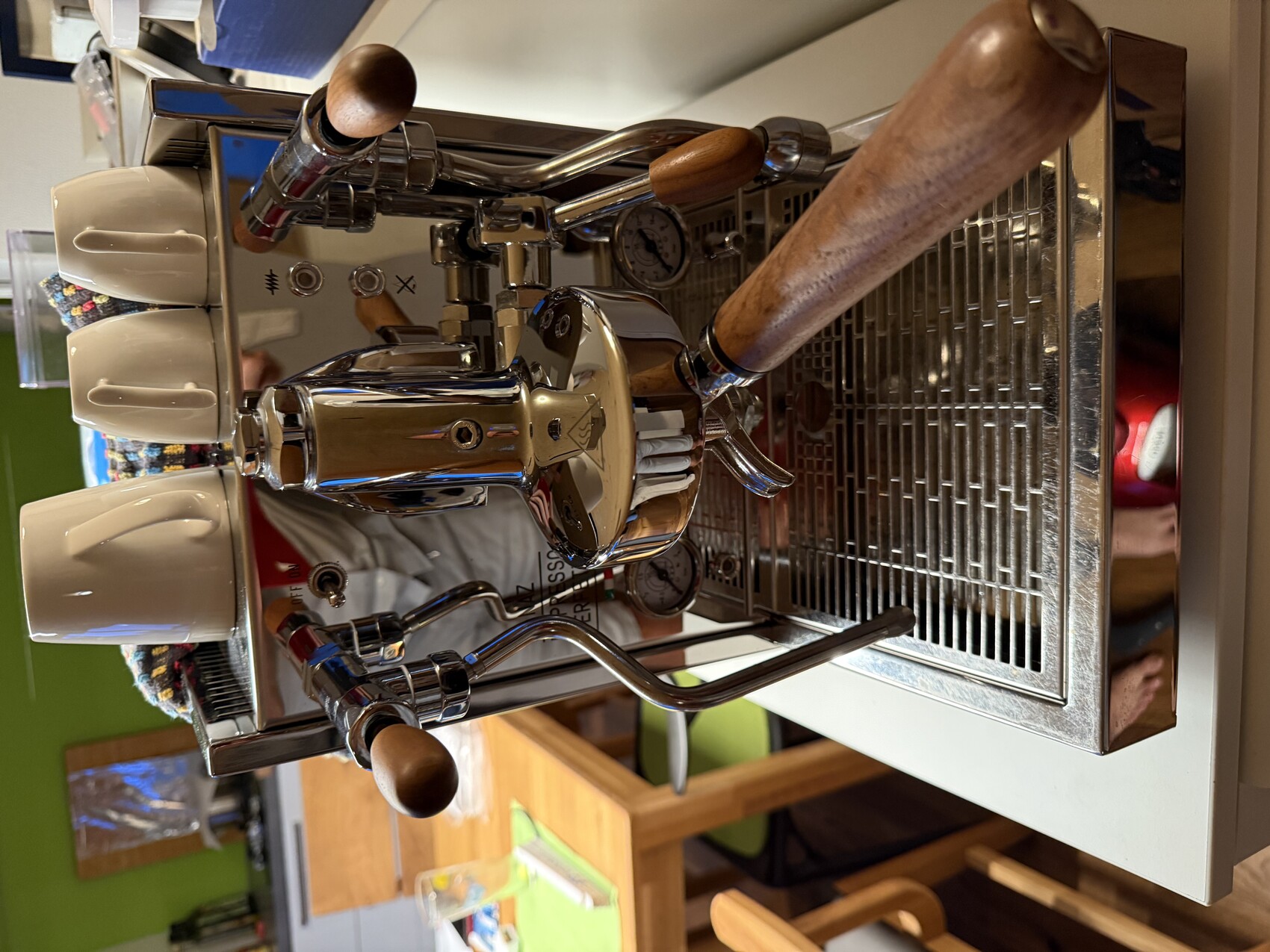 Espressomaschine aus Edelstahl mit zwei Brühgruppen, Holzgriff-Portafilter, Tassen oben.
