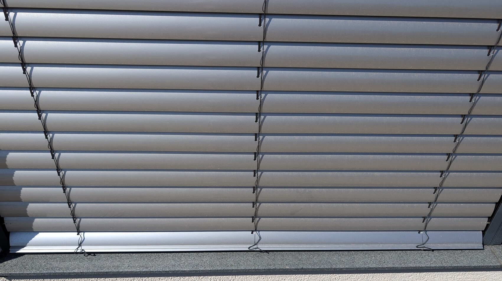 Metal blinds with horizontal slats and cords for fixing
