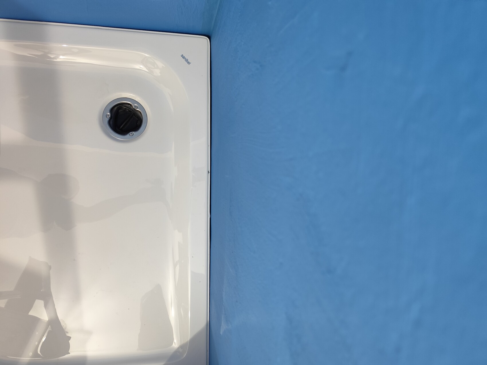 White casing with black control knob in front of blue wall.