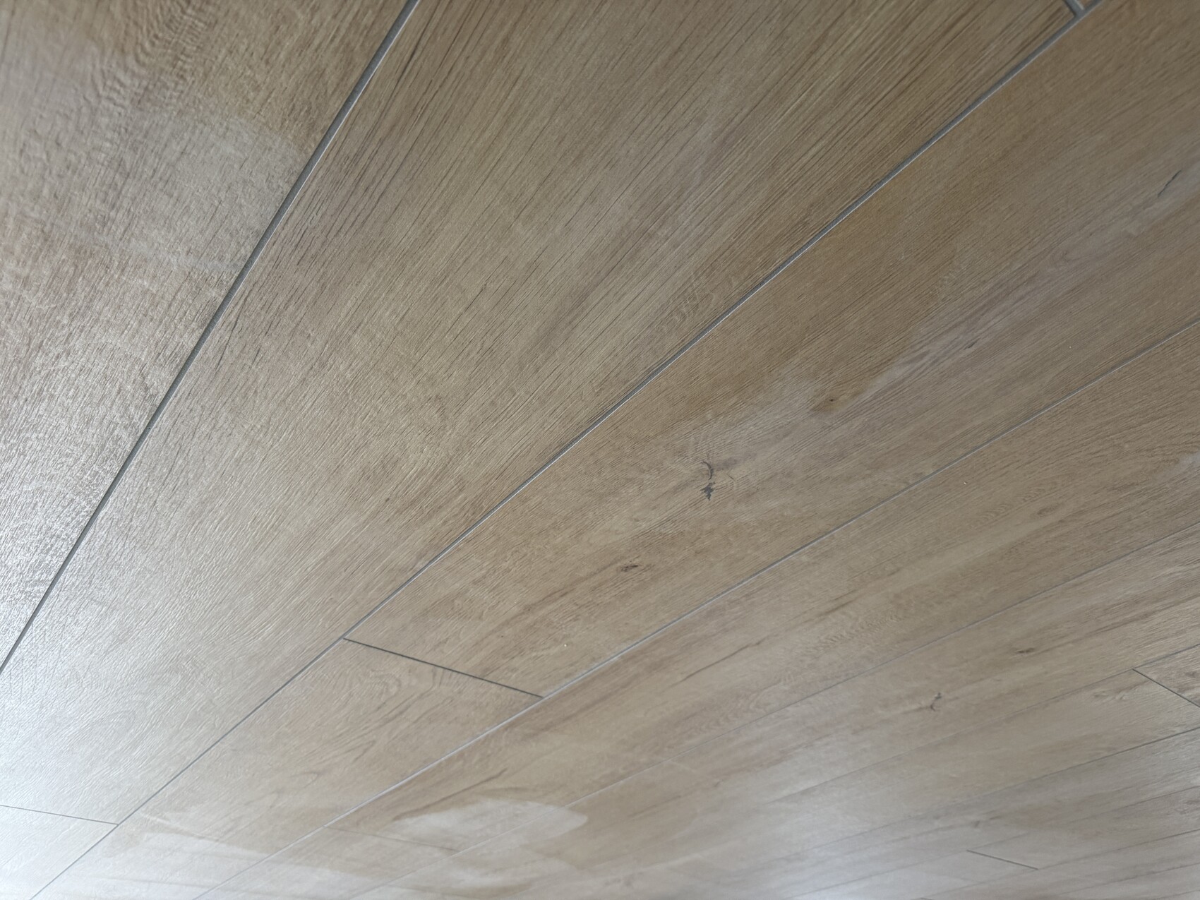 Light wooden floor with long planks, visible grain and joints.