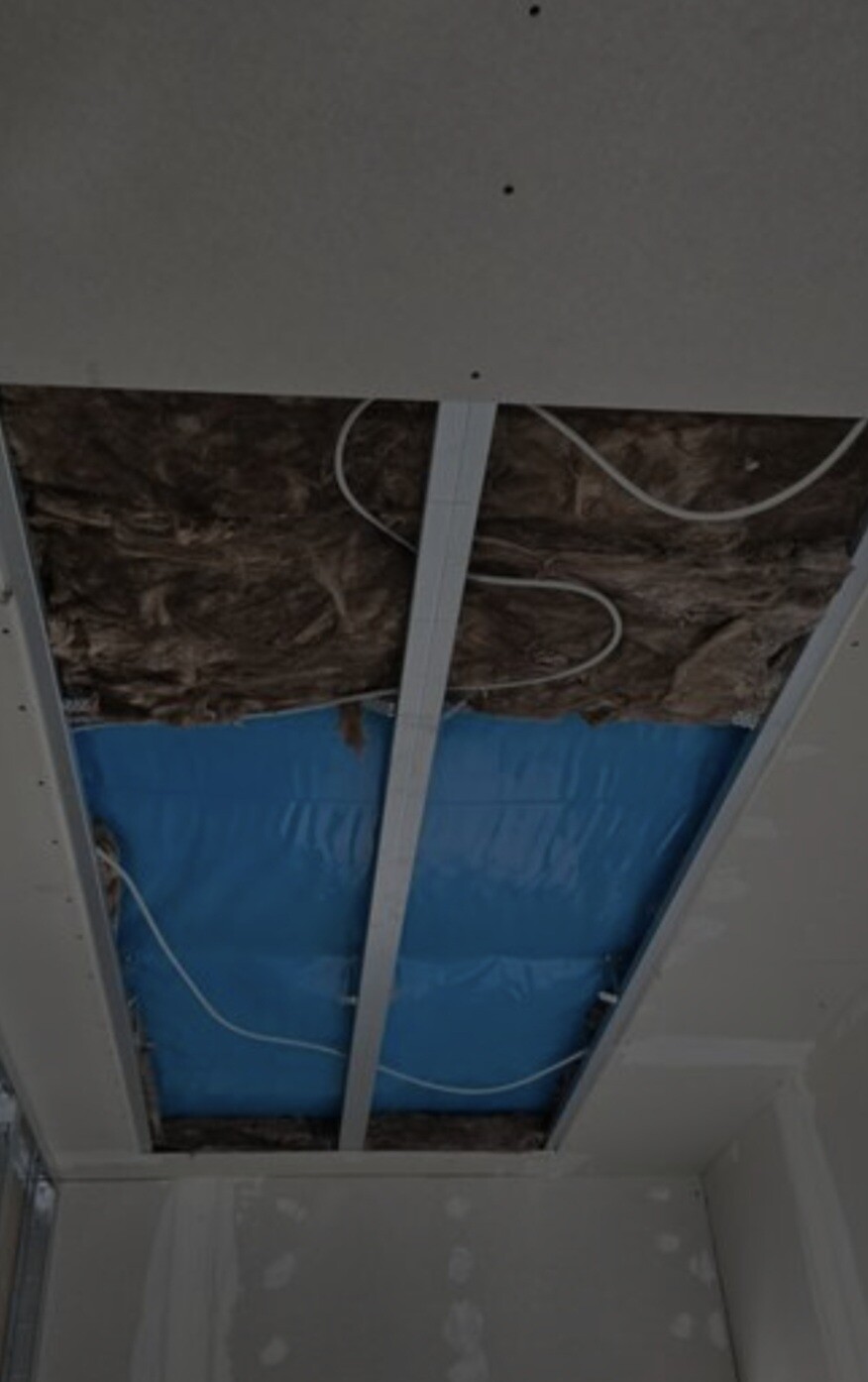 Ceiling opened: insulation, metal beams, blue vapor barrier, and loose cables visible