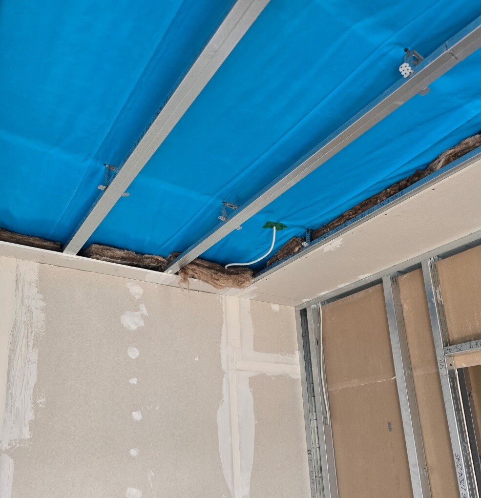 Unfinished interior with blue cover foil on the ceiling, metal beams and cables.