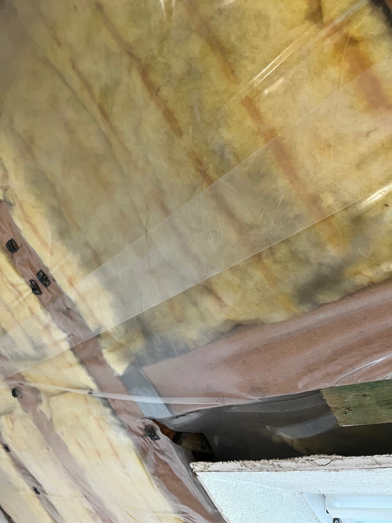 Yellow glass wool insulation behind transparent plastic, wooden frame and components visible.