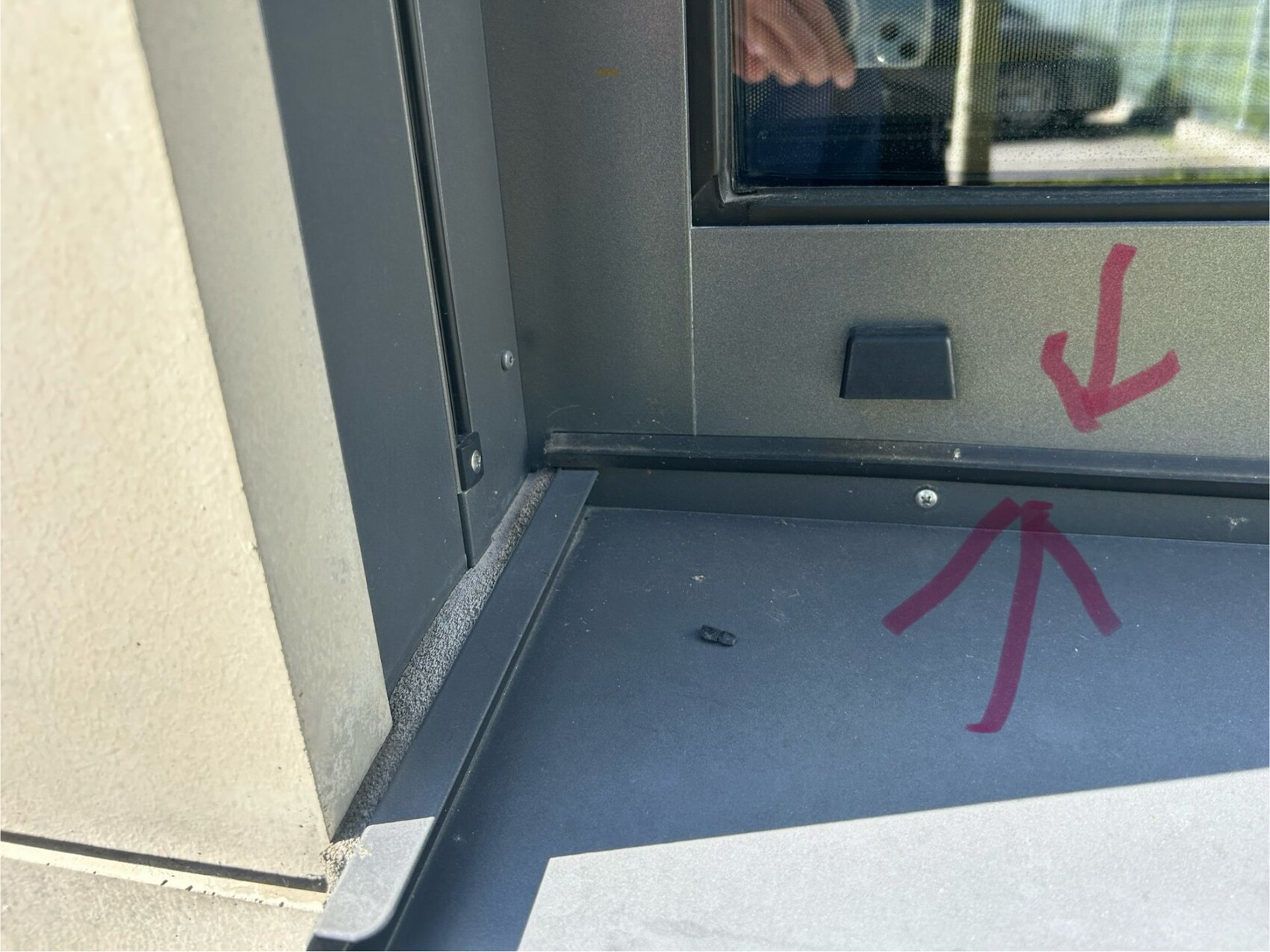 Close-up of window frame at the base area with pink arrows pointing to the gap