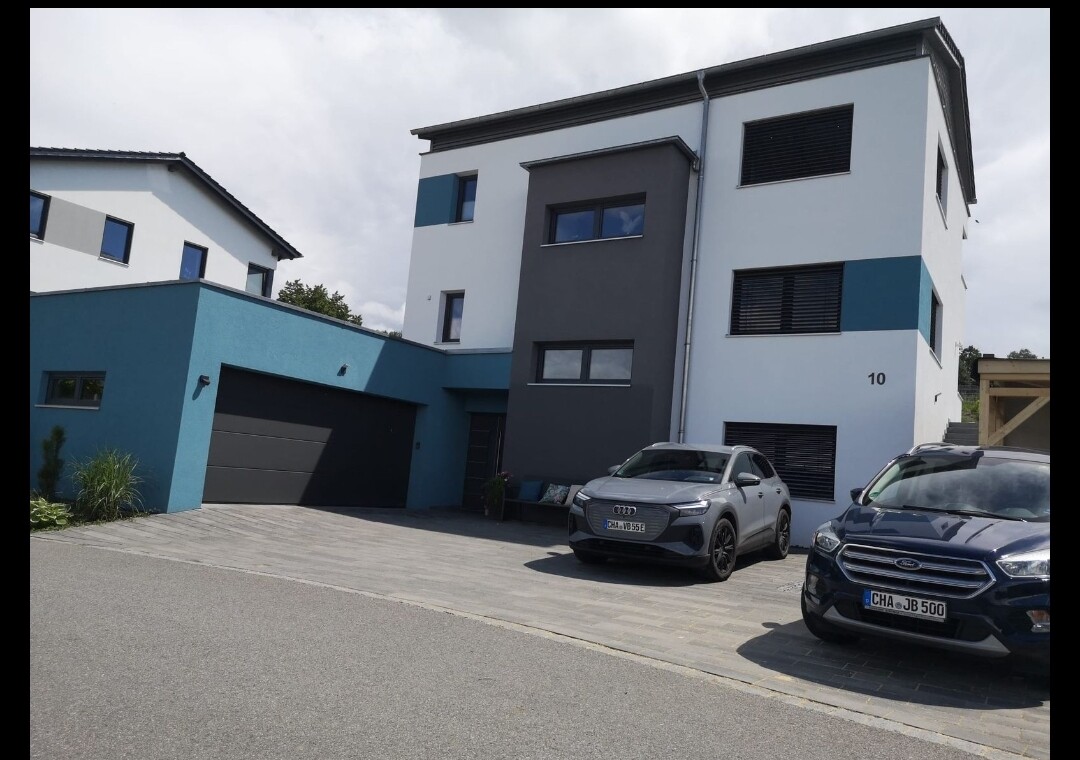 Modern two-story house front with garage and two cars in the driveway.
