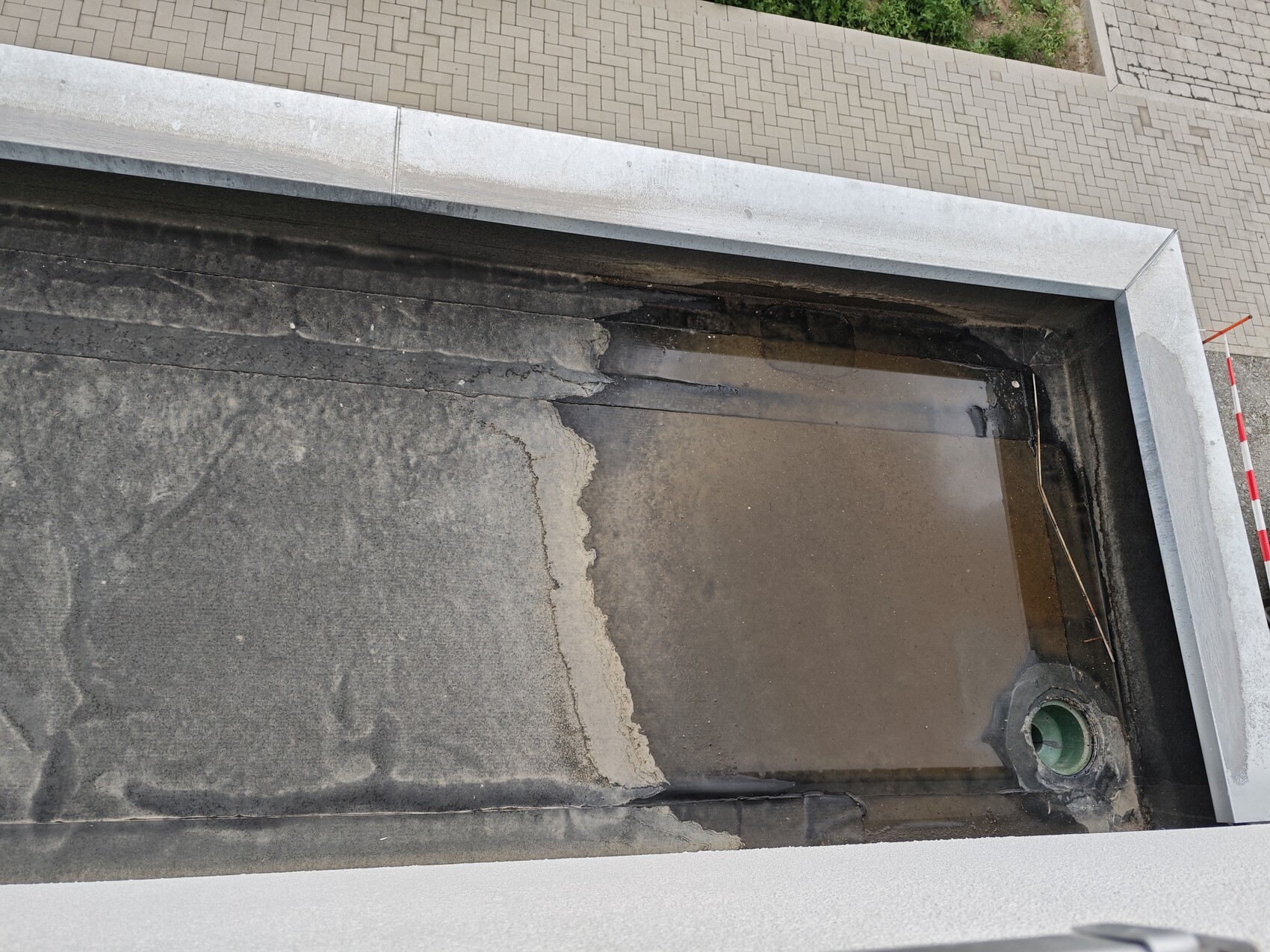 Flat roof with visible waterproofing, standing water and roof edge drain