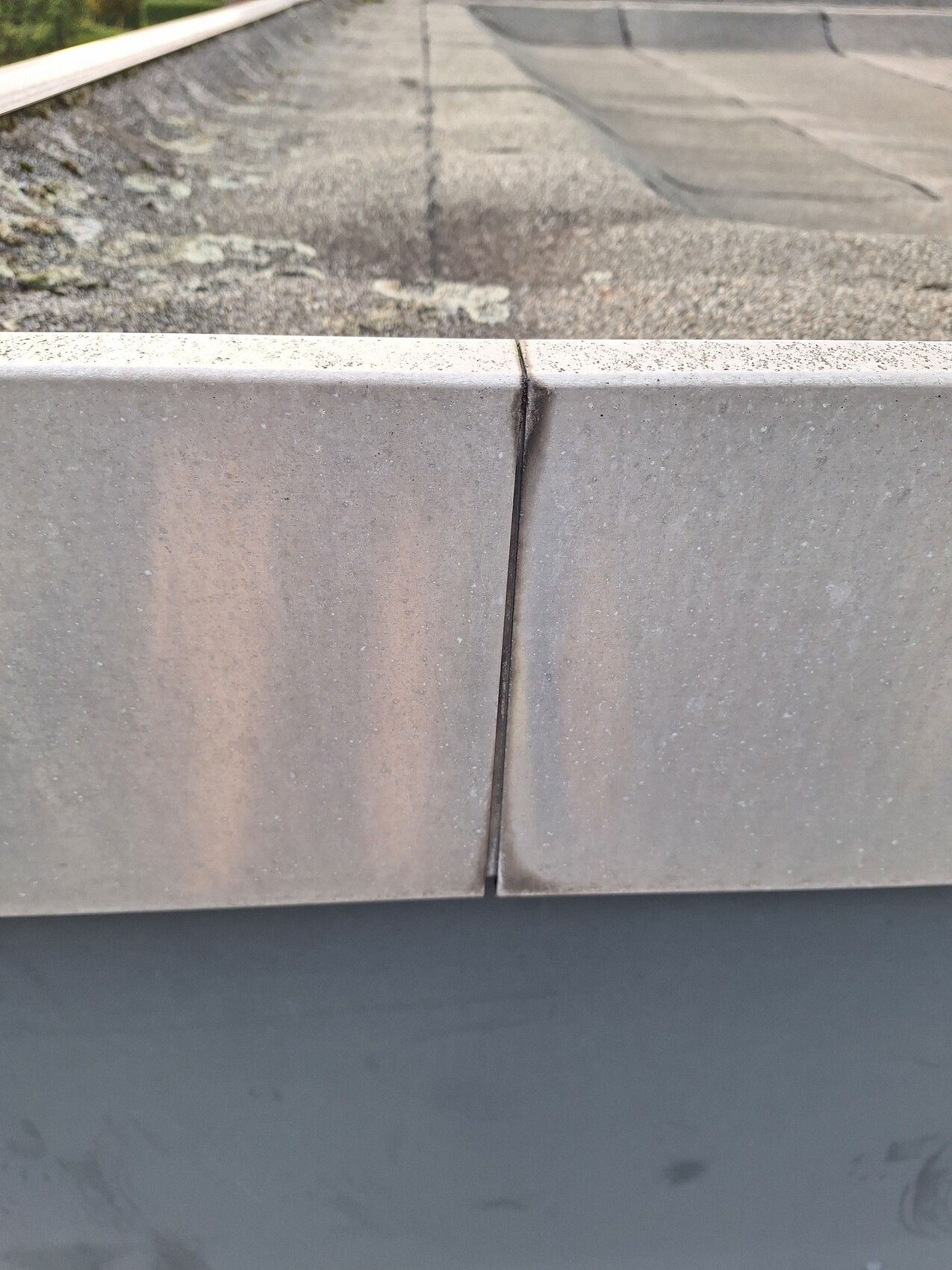 Close-up of a roof edge made of concrete blocks with joints, roof surface with moss spots.
