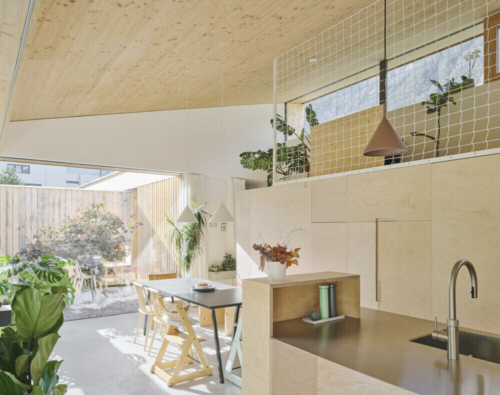 Open kitchen with dining table, wood ceiling, stone tiles, sink, and green potted plants