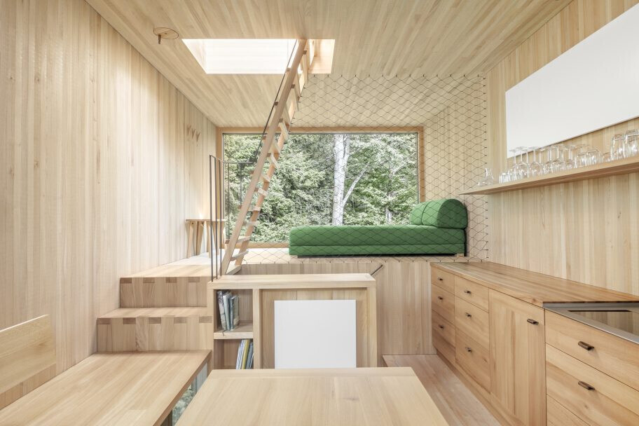 Bright living space with wood-look finish and staircase to loft, green sofa corner.