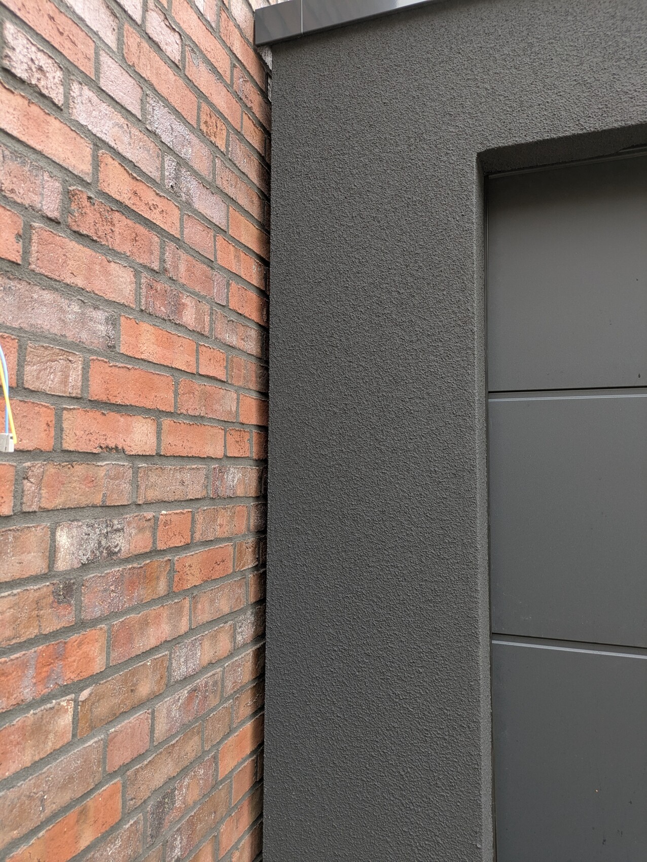 Exterior view: dark door front next to red brick wall