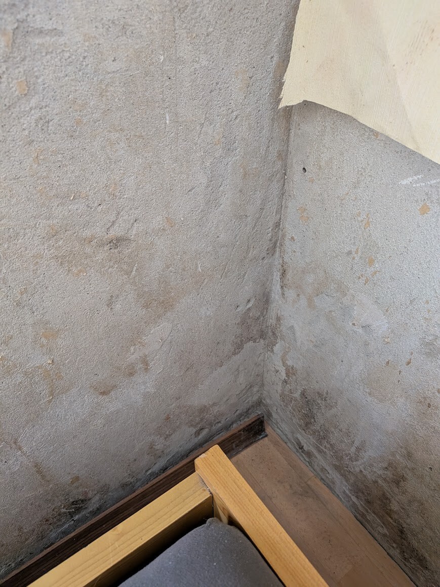 Basement wall with moisture and plaster damage in the corner.