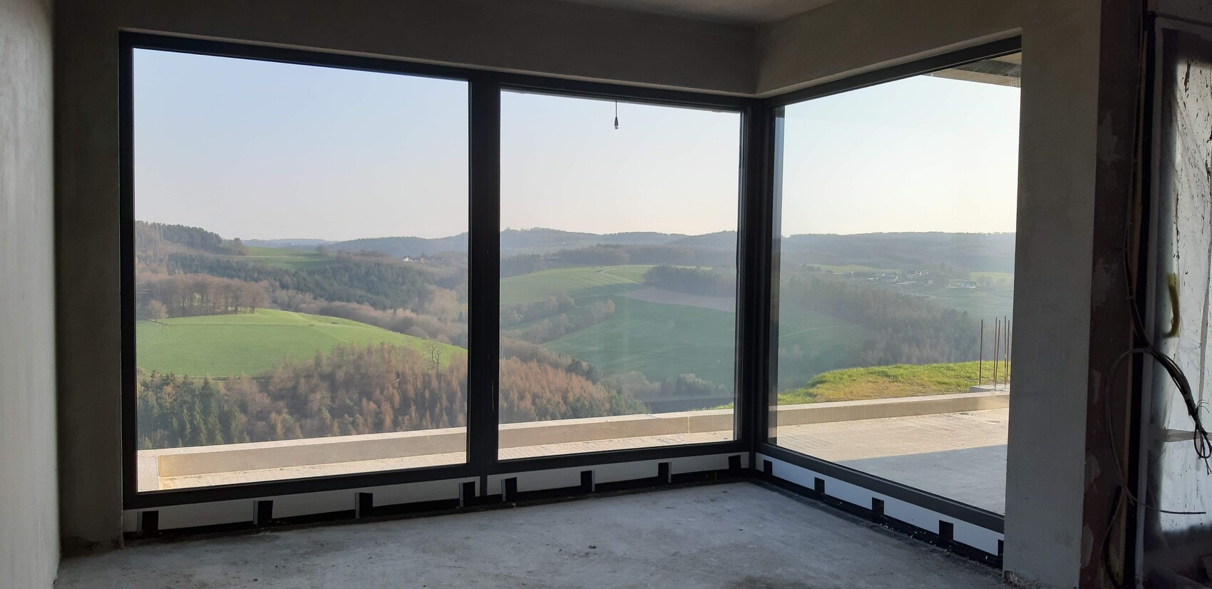 Unfinished interior with large corner windows and view of green landscape