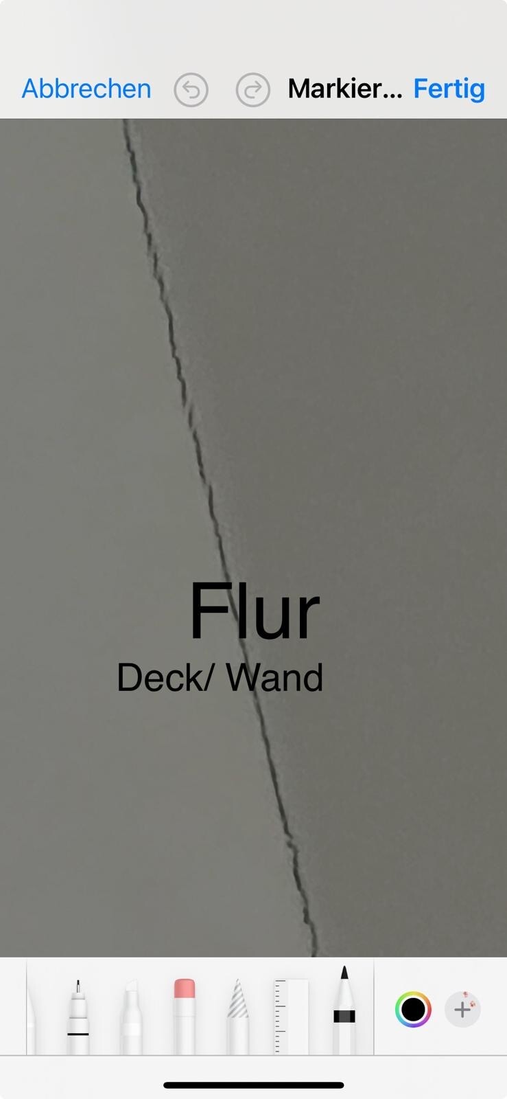 Diagonaler Wandriss im Flur an grau verputzter Wand.