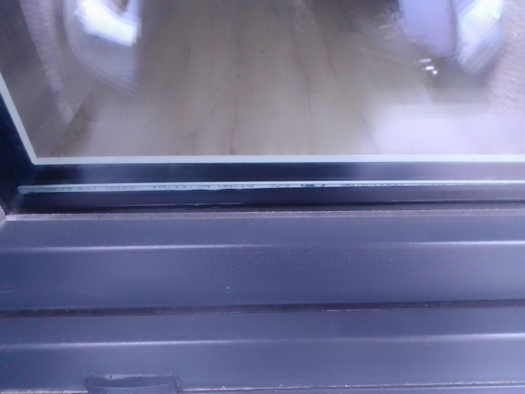 Close-up of a black window frame with glass and seal.