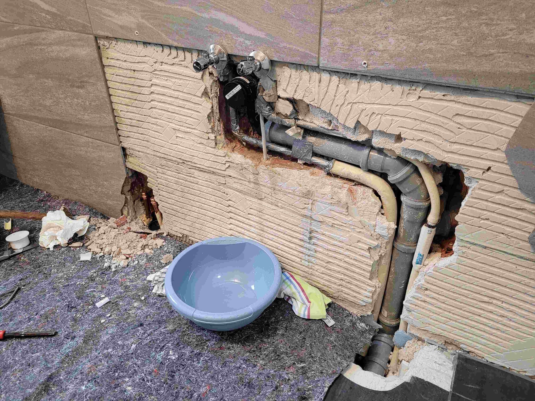 Open wall with pipes and damaged plaster during construction work