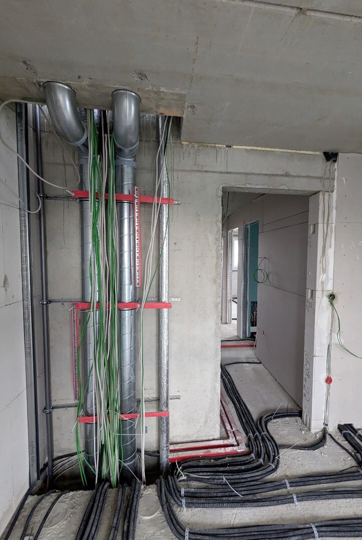 Rohbau Innenbereich mit sichtbaren Kabeln, Rohren und Installationen der Haustechnik