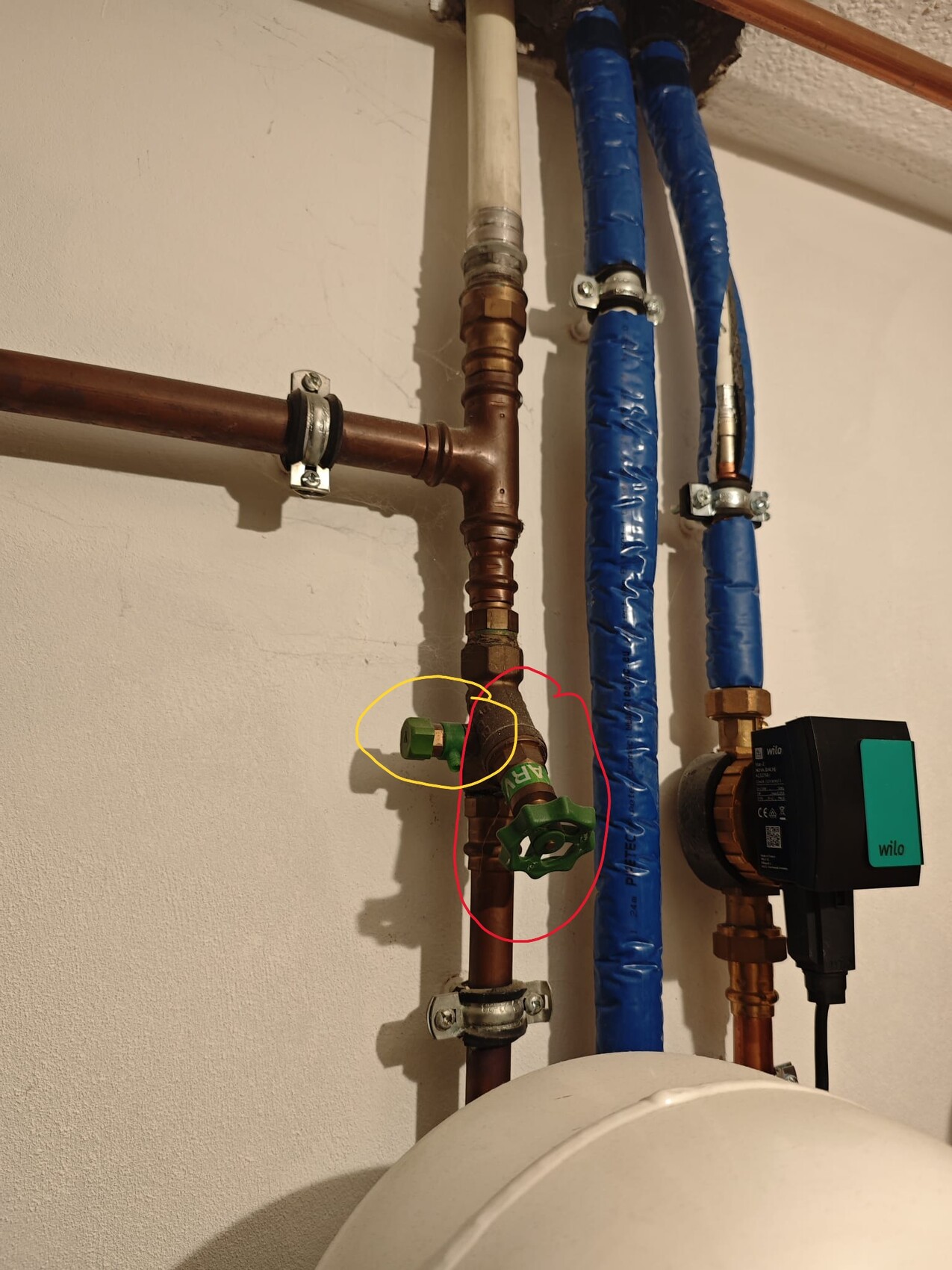 View of installation pipes in the basement with green shut-off valve and Wilo circulation pump