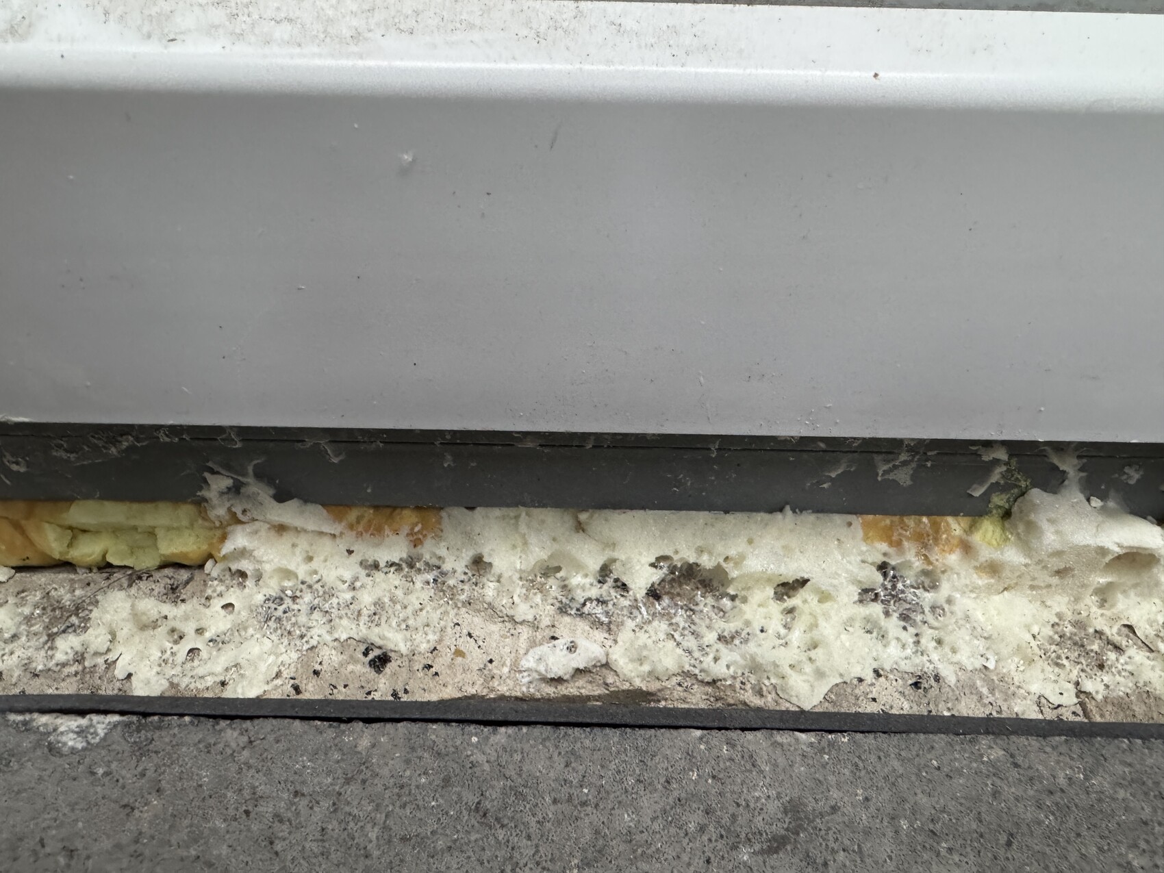 Close-up of a building facade with visible foam insulation between wall and foundation.
