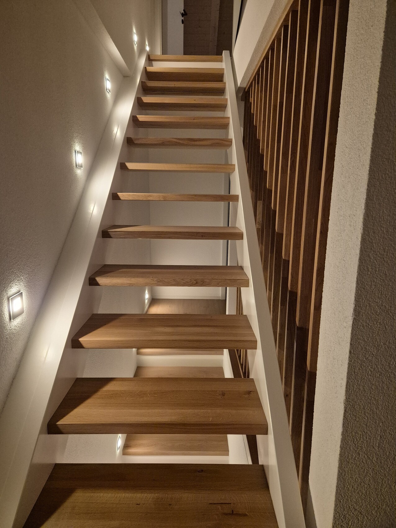 Modern wooden staircase with railing in a bright interior hallway