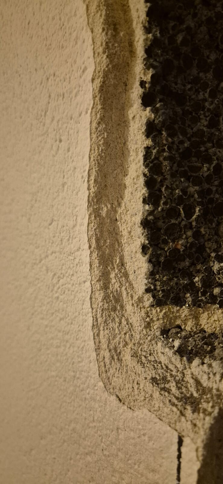 Close-up of a wall with a rough surface and black gravel texture