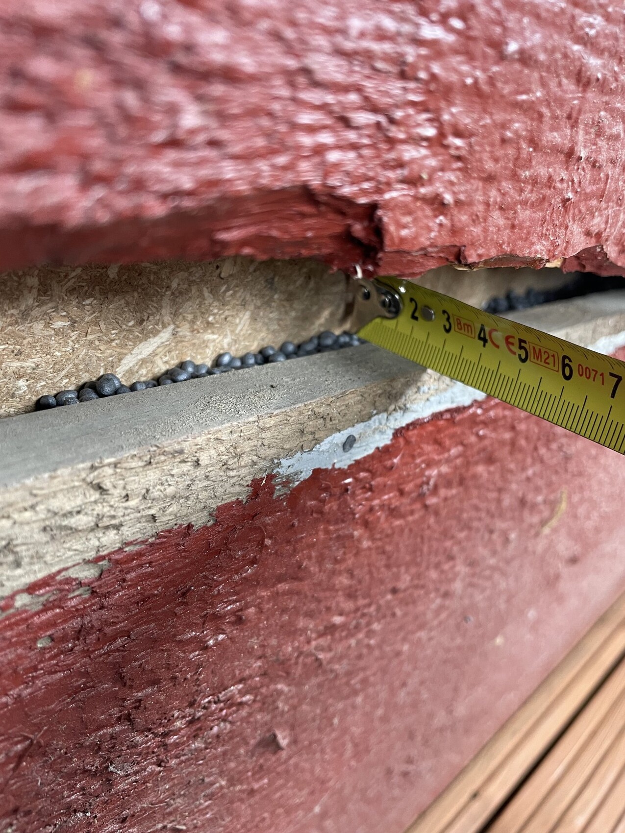 Close-up of a red brick wall with measuring tape and construction defects