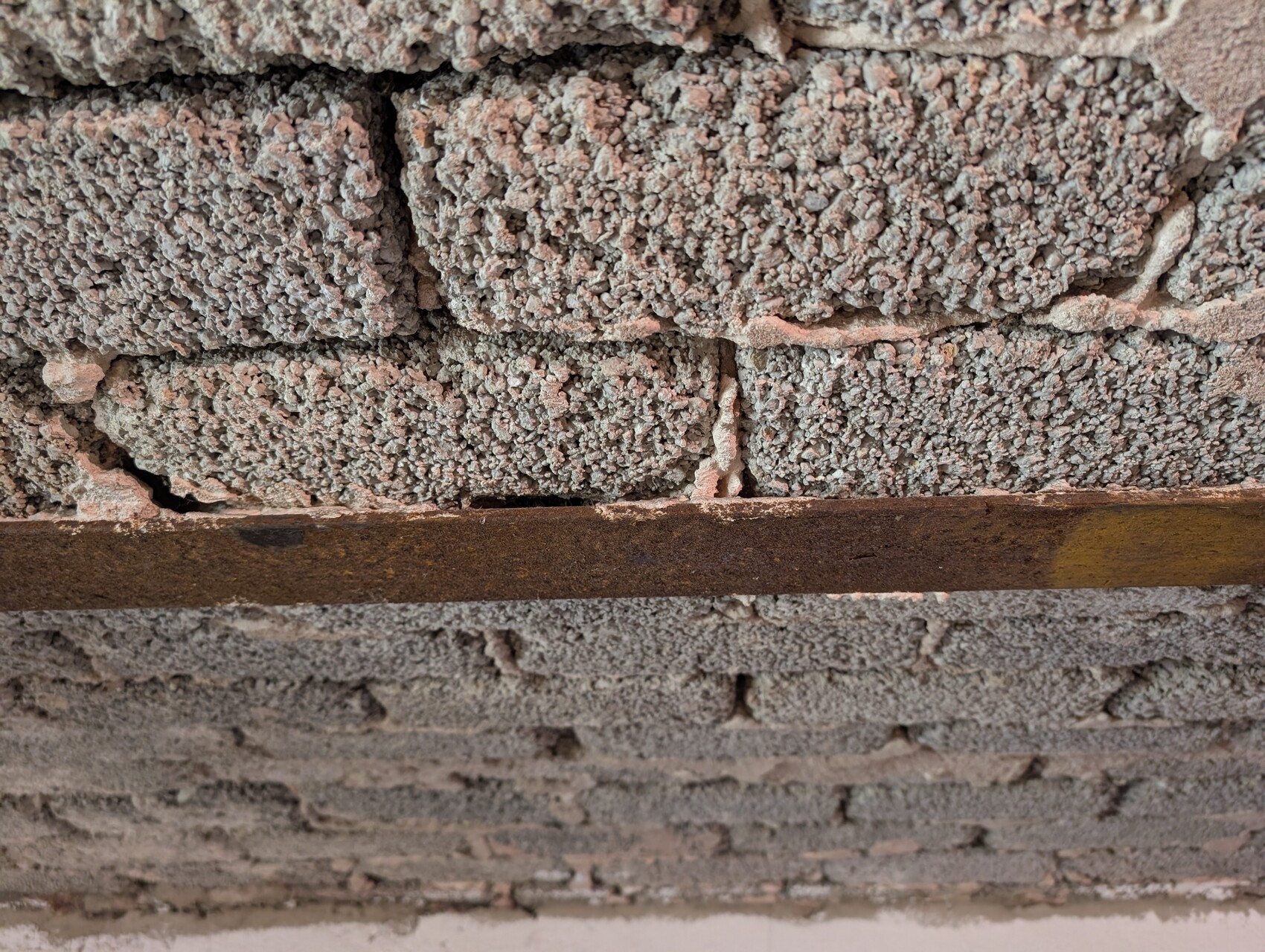 Shell wall made of bricks with rough mortar and rusty steel beam