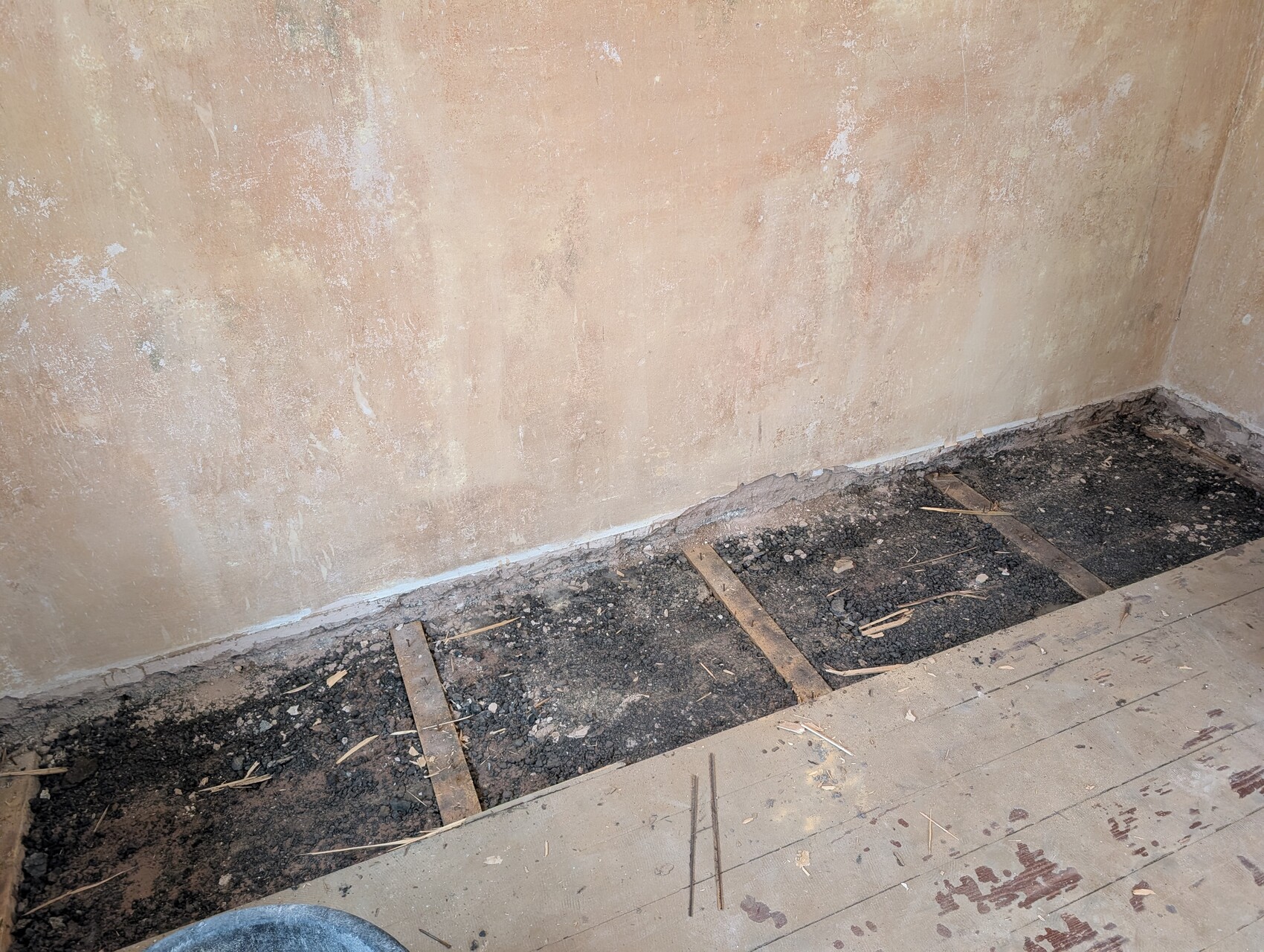 Room with open excavation at floor level, earth, wooden joists and renovation work