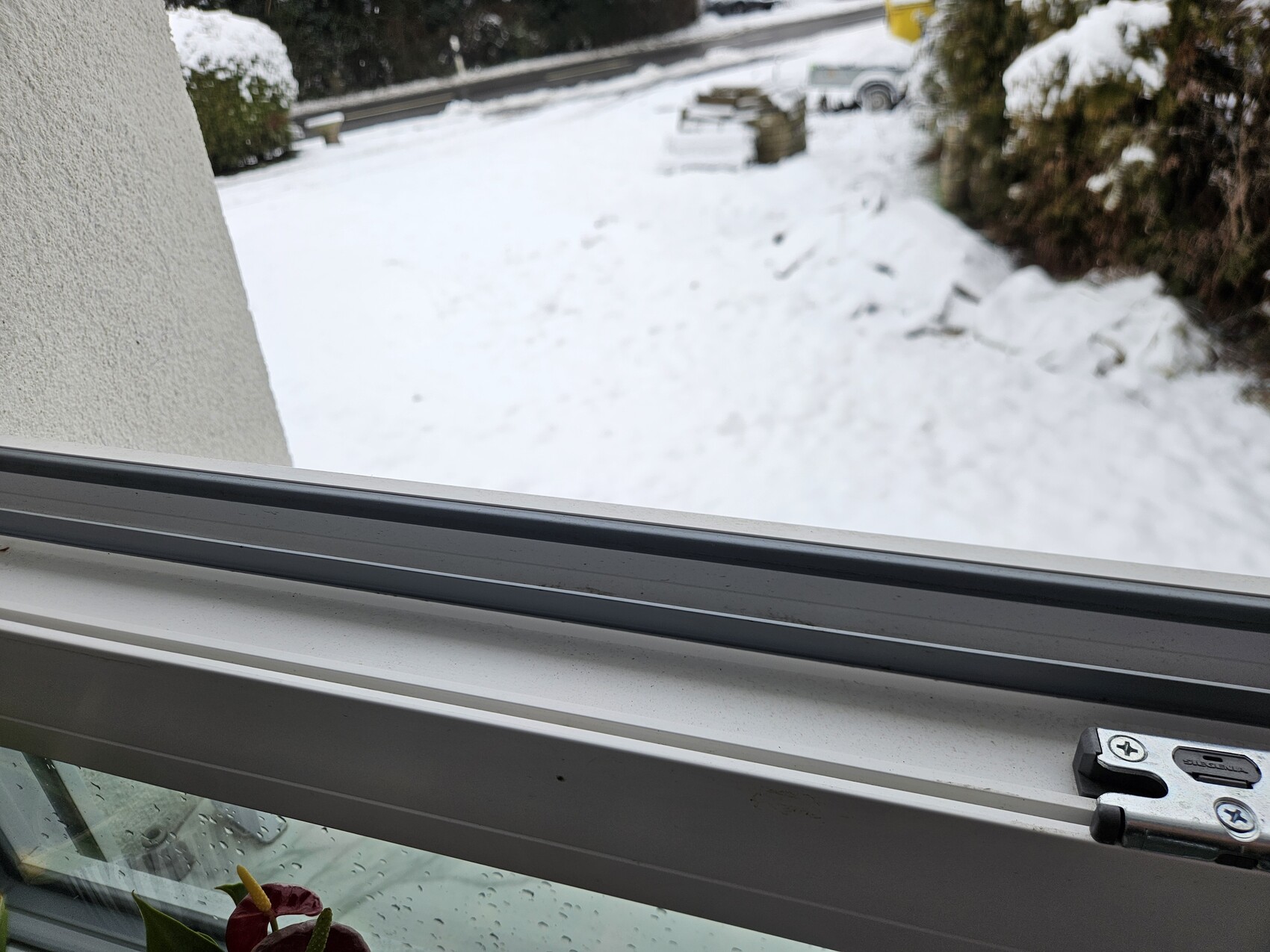 View from the window of a snow-covered outdoor area with a car in the background.