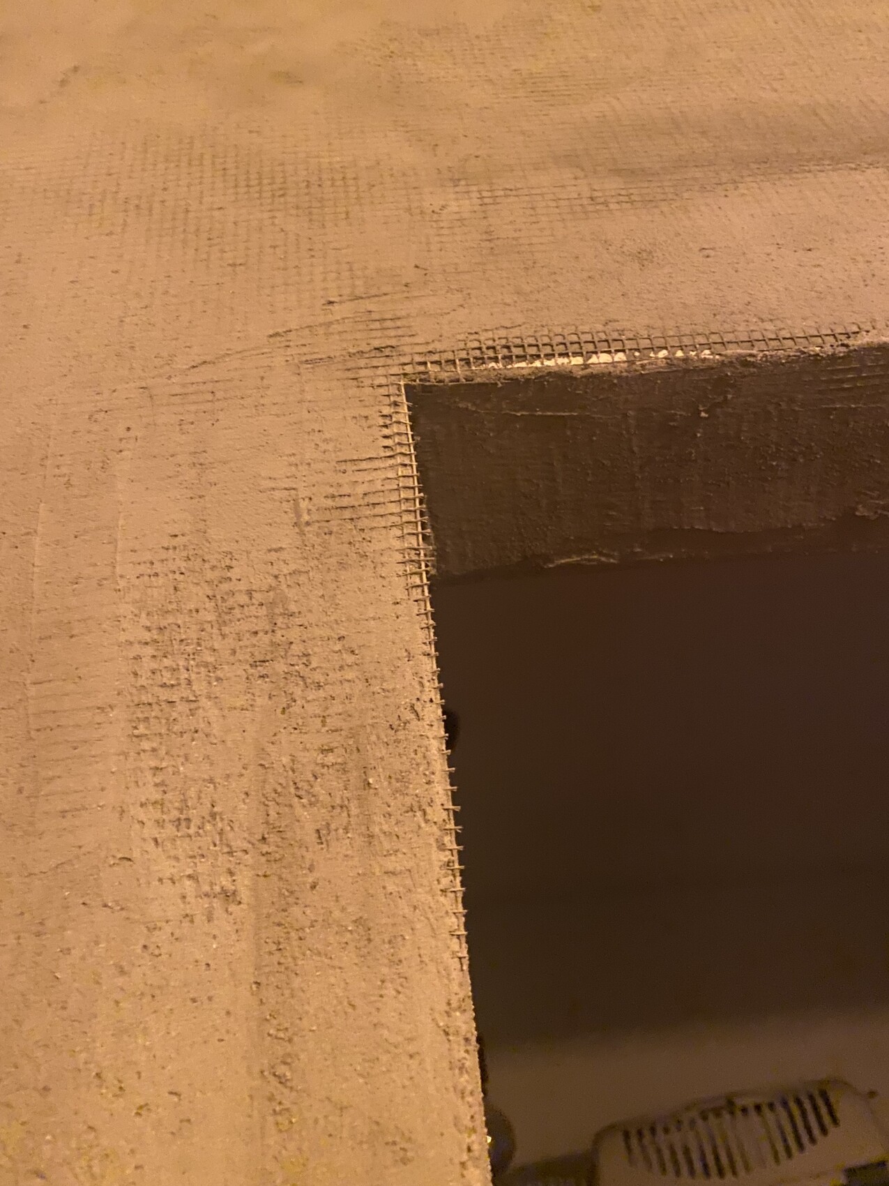Interior shell construction scene with rough plaster and metal mesh edging at an opening