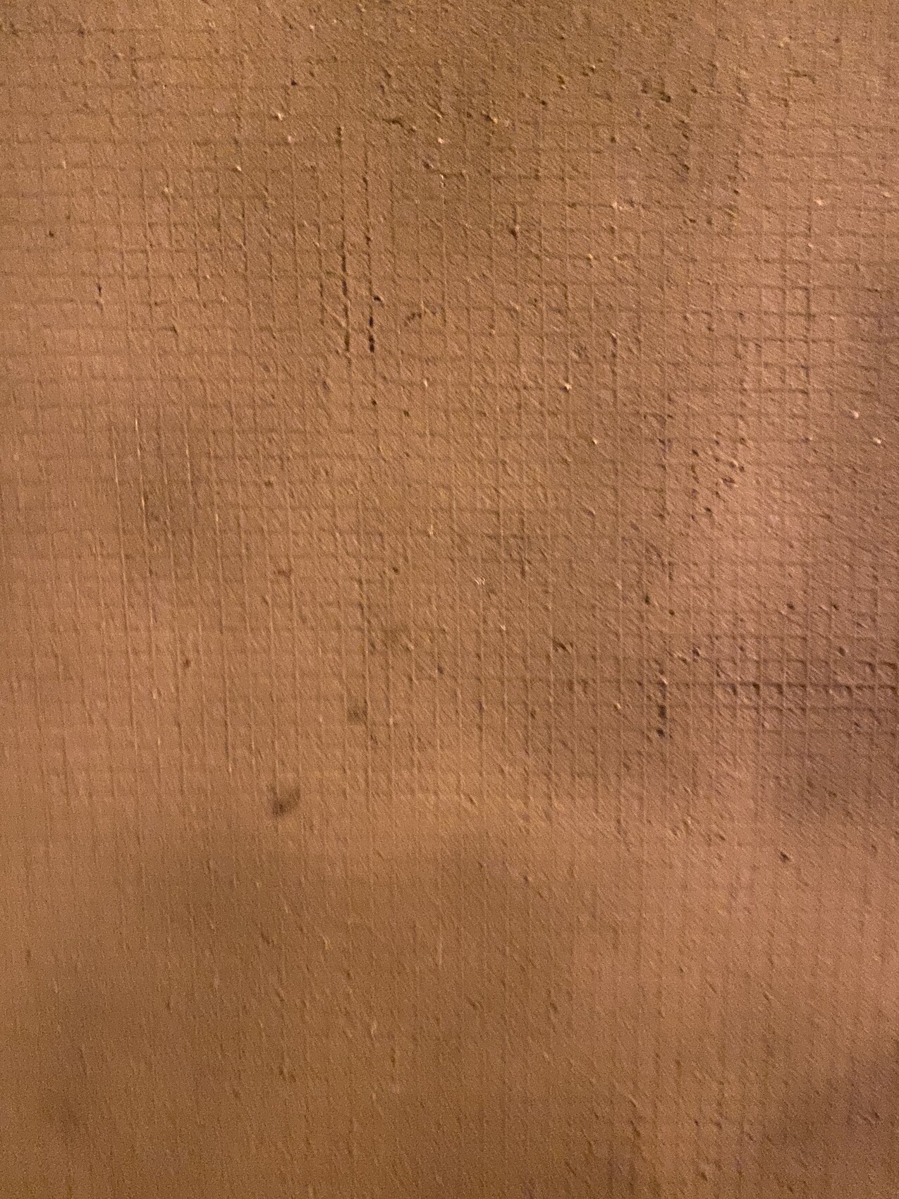 Close-up of a brown wall surface with plaster texture and grooves