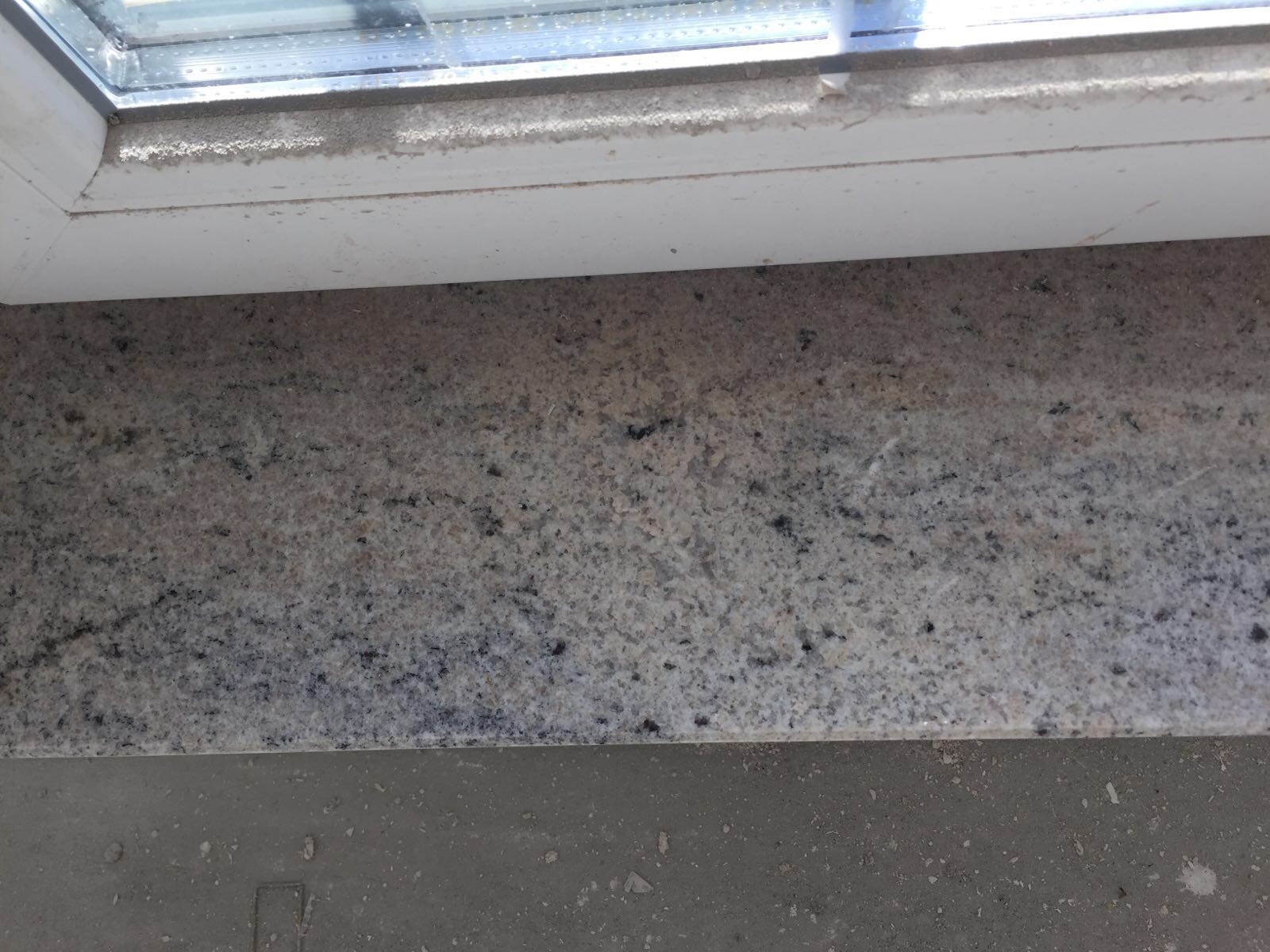 Fensterbank aus Granit neben Fensterrahmen in roher Bauumgebung