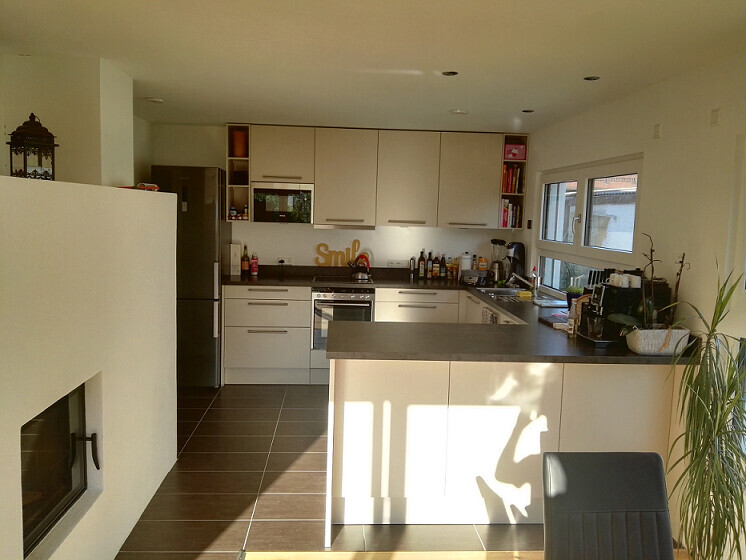 Bright modern kitchen with central island, white cabinets, oven, and refrigerator.