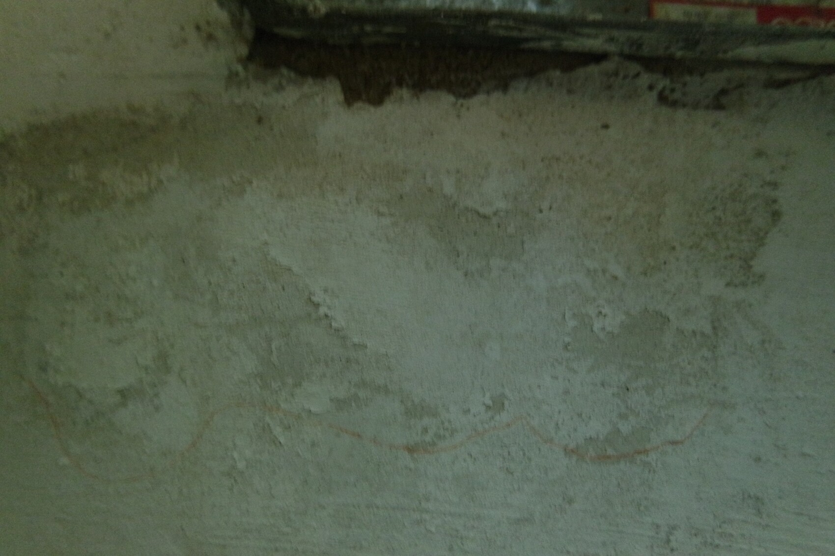 Basement wall with damp spots and peeling plaster in a construction environment