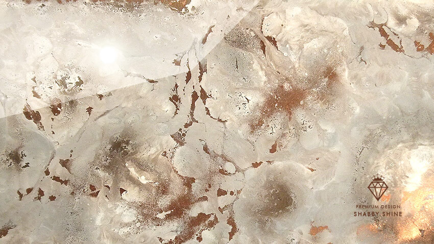 Close-up of a marble-like stone surface with brown spots and light reflections