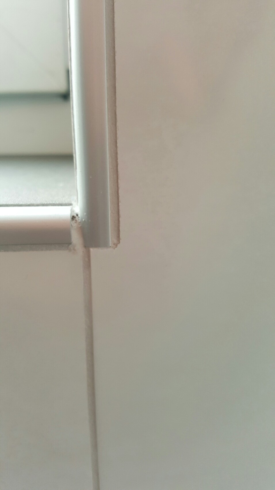 Close-up of a white window frame with damaged wall edges