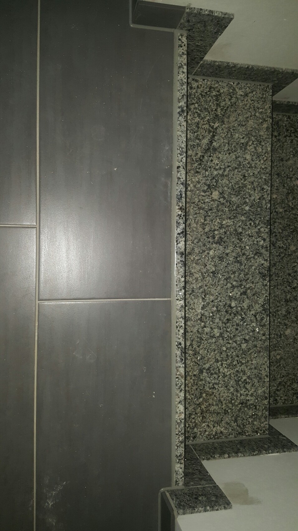 Kitchen area with dark granite countertop and dark tiles