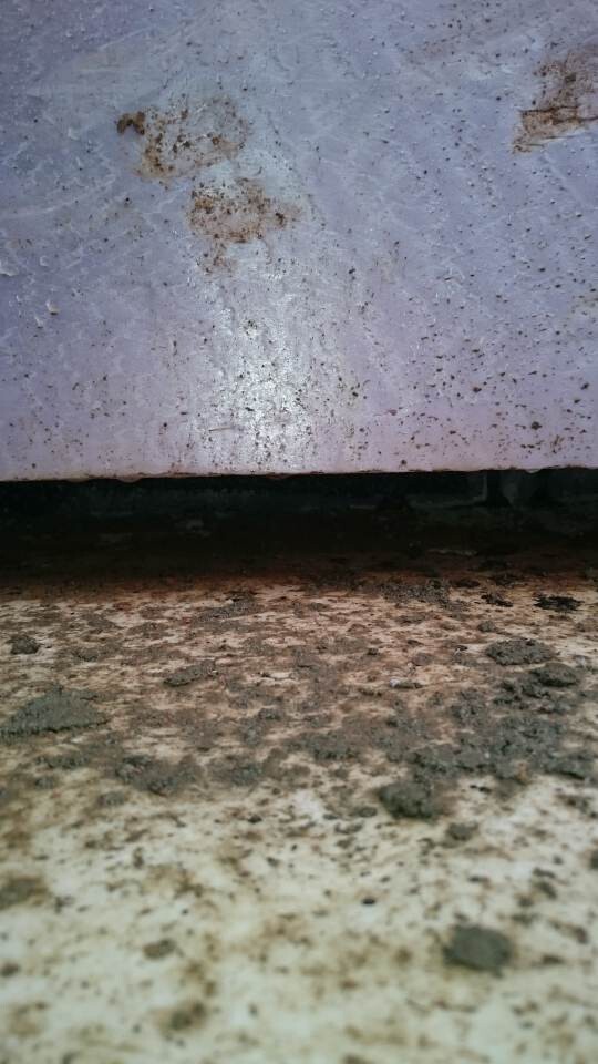 Close-up of a rusty metal surface over a dirty concrete floor