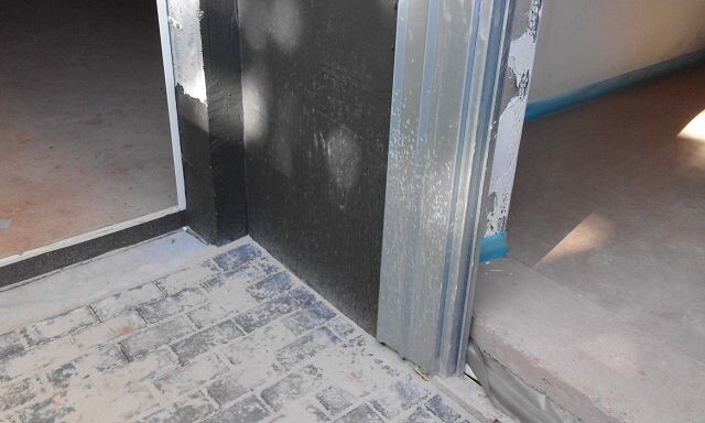Unfertiger Eingang im Rohbau mit Metall-Tuerrahmen und Bauabdichtungen