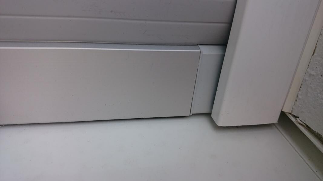 Close-up of a white door bottom edge with sealing profile on the floor.